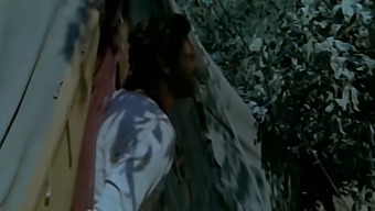A Married Woman Engages In Sexual Activity With A Black Man While Her Husband Is Nearby, Observing From Behind Some Bushes